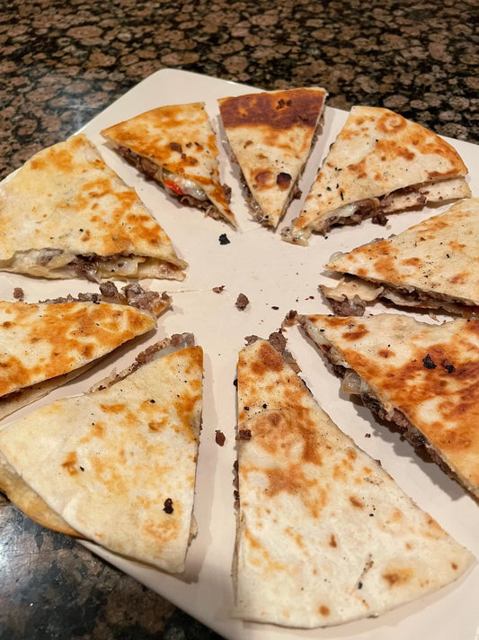 A plate of golden-brown quesadilla slices with a visible meat and cheese filling.